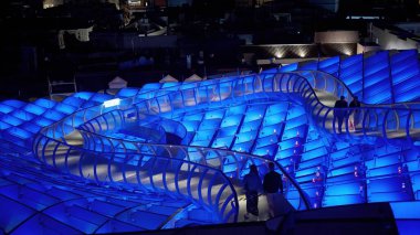 Metropol Şemsiyesi 'nin yükseltilmiş geçidi Sevilla, İspanya' da yürüyen insanlarla geceleyin mavi ışıkla aydınlanıyor - SEVILLE, SPAIN - 25 Mart 2025