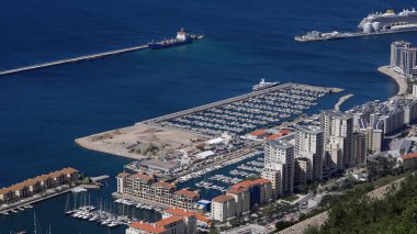 Cebelitarık 'taki Ocean Village marinasının güneşli bir günde lüks yatlar, konut binaları ve bir yolcu gemisinin yer aldığı hava manzarası - GIBRALTAR, İngiltere - 31 Mart 2025