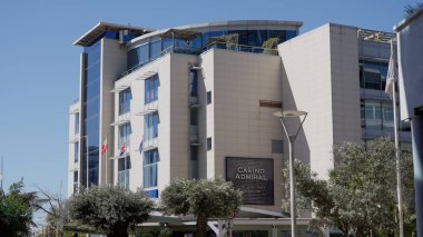 Güneşli bir günde Cebelitarık 'ta rüzgarda dalgalanan bayraklı modern kumarhane binası - GIBRALTAR, İngiltere - 31 Mart 2025