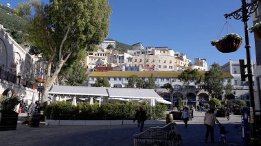 Casemates Meydanı, Cebelitarık 'ta güneşli bir günün tadını çıkaran insanlar, renkli binalar ve arka planda Cebelitarık Kayası - GIBRALTAR, İngiltere - 31 Mart 2025