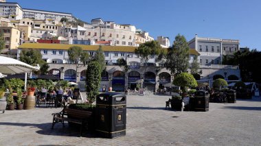 Güneşli bir günde Gibraltar 'daki Casemates Meydanı' ndaki restoran ve banklarda oturan insanlar - GIBRALTAR, İngiltere - 31 Mart 2025