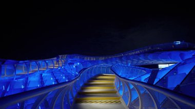 Gece mavi neon ışıklarıyla aydınlatılan modern yaya köprüsünün alçak açılı görüntüsü - SEVILLE, SPAIN - 25 Mart 2025