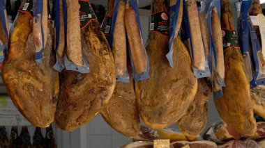 Serrano jambon bacakları geleneksel bir İspanyol pazarında kancalardan sarkıyordu, satışa hazırdı - CADIZ, SPAIN - 27 Mart 2025