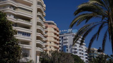 İspanya 'nın güneyindeki Costa del Sol' da popüler bir turizm merkezi olan Marbella 'daki yerleşim yerleri ve palmiye ağaçları - MARBELLA, SPAIN - 30 Mart 2025