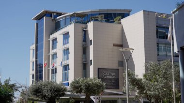 Güneşli bir günde Cebelitarık 'ta rüzgarda dalgalanan bayraklı modern kumarhane binası - GIBRALTAR, İngiltere - 31 Mart 2025