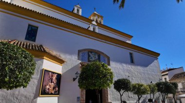 Beyaz cephe Ermita del Santo Cristo de la Vera Cruz Kilisesi 'nin sarı detaylarıyla, Marbella, İspanya' da güneşli bir yaz gününde - MARBELLA, İspanya - 30 Mart 2025