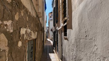 Marbella, İspanya 'da yıpranmış duvarları ve parmaklıklı pencereleri olan güneş ışığı aydınlatan dar bir sokak - MARBELLA, İspanya - 30 Mart 2025