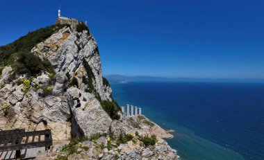 Mavi gökyüzü altında Akdeniz 'e bakan bitki örtüsü ve binalarla Cebelitarık kayasının manzarası - GIBRALTAR, İngiltere - 31 Mart 2025
