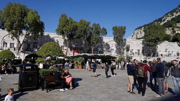 Güneşli Grand Casemates Meydanı 'nın tadını çıkaran turistler açık hava restoranları ve arka planda ünlü Cebelitarık Kayası - GIBRALTAR, İngiltere - 31 Mart 2025
