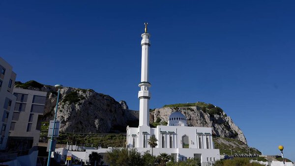 Низкий угол обзора мечети короля Фахада ибн Абдул-Азиза аль-Сауда с минаретом и арабскими надписями, сияющими под ясным голубым небом - ГИБРАЛТАР, Великобритания - 31 марта 2025 года