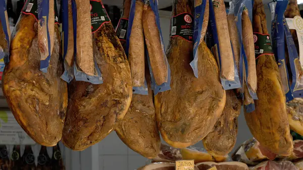 Serrano jambon bacakları geleneksel bir İspanyol pazarında kancalardan sarkıyordu, satışa hazırdı - CADIZ, SPAIN - 27 Mart 2025