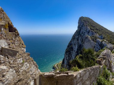Fas Kalesi 'nin harabelerinden panoramik manzara, Cebelitarık Kayası, Akdeniz ve uzak bir kargo gemisi sergileniyor.