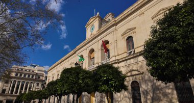 Seville Belediye Binası. Güneşli bir günde Endülüs ve İspanyol bayrakları sergilenen bir hükümet binası.