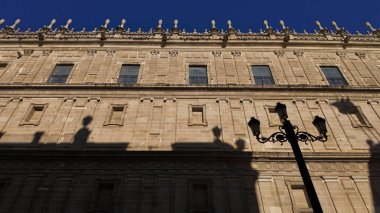 İspanya 'nın Sevilla kentindeki Hint Adaları Arşivi' nin ön cephesinde mavi gökyüzünün altında bir sokak lambasının alçak açılı görüntüsü.