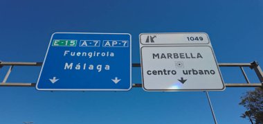 Mavi gökyüzü güneşli bir günde Marbella şehir merkezine, Fuengirola ve Malaga 'ya giden yolu gösteren yol işaretleri.