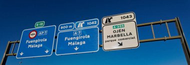 İspanya 'da açık mavi gökyüzünün altında Fuengirola, Malaga, Marbella ve Ojen' e giden yolu gösteren tabelalar.