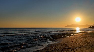 İspanya, Marbella 'nın sakin denizi üzerinde batan güneş, suyun üzerinde altın bir yansıma yaratır.