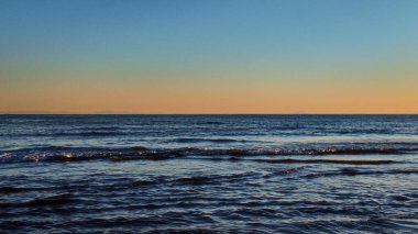 Gün batımında Marbella sahilini yavaşça yıkayan küçük dalgalar Cebelitarık 'ın silueti uzaktan görülebiliyor.