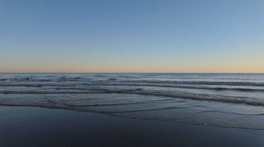 Durgun deniz dalgaları, renkli bir günbatımında İspanya 'nın Marbella sahilini nazikçe yıkıyor.