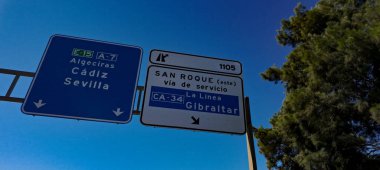 Yol işaretleri Cebelitarık, Algeciras, Cadiz, Seville, San Roque ve La Linea yönlerini gösteriyor açık mavi gökyüzüne karşı