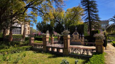 İspanya, Seville 'deki Maria Luisa Parkı' nın canlı güzelliği güneşli bir günde, yemyeşil, süslü detaylar ve mimari çekiciliğini ön plana çıkarıyor.