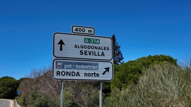 İspanya 'nın Ronda şehrinde açık mavi gökyüzünün altında farklı noktalara giden yolları gösteren yol işaretleri.
