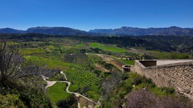 Ortaçağ şatosundan görülen yeşil tarlaları, dağları ve açık mavi gökyüzü ile Ronda 'nın vadisinin nefes kesici manzarası.