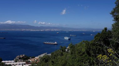Kargo gemileri güneşli bir günde Algeciras yakınlarındaki Cebelitarık Körfezi 'nde, dağlarla birlikte yol alıyorlar.