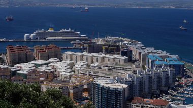Cebelitarık limanına yanaşan büyük yolcu gemisi ön planda konut ve ticari binalar görünüyor.