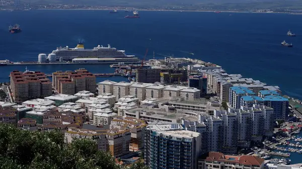 Cebelitarık limanına yanaşan büyük yolcu gemisi ön planda konut ve ticari binalar görünüyor.