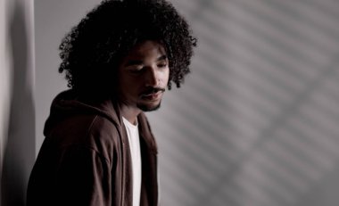 Depresyondan muzdarip genç Afro-Amerikalı adam duvarın kenarına bakıyor.