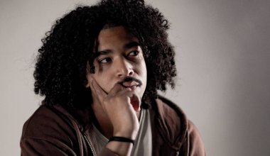 Genç öğrenci çenesinde el ele tutuşup geleceği düşünüyor.