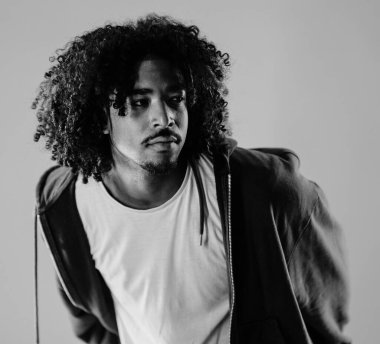 Siyah beyaz, kıvırcık saçlı genç bir Afro-Amerikan 'ın bir stüdyo çekimine bakışları.