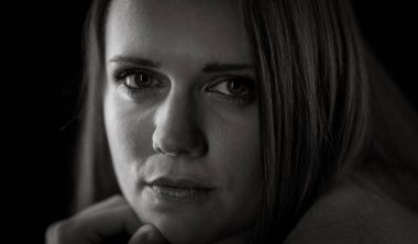 Siyah beyaz bir fotoğrafta eli çenesinde poz veren kendinden emin genç bir kadının portresi.