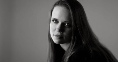 Profesyonel stüdyo ortamında uzun saçlı, büyüleyici genç bir kadının siyah beyaz portresi.