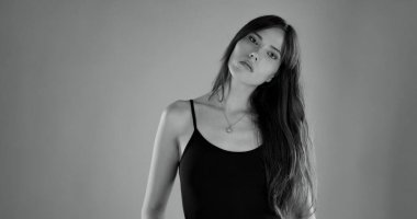 Uzun saçlı, siyah bluz ve kolye takan güzel bir kadının stüdyo portresi.