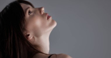 Bir mankenin yüzünü ve boynunu kapayarak, gri arka planda hafif ışıklandırmayla aydınlatmış.