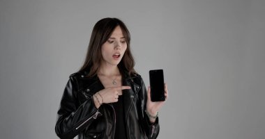 Akıllı telefonuna şaşırmış bir ifadeyle bakan genç bir kadın mesajınız veya uygulamanız için boş bir ekran sunuyor.