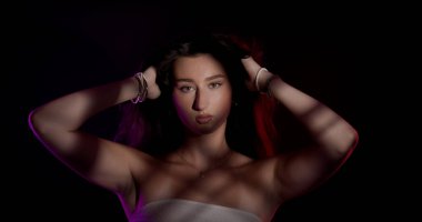 Saçlarını renkli ışıklar ve gölgelerle tutan güzel bir kadının stüdyo portresi.