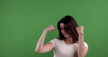 Kaslarını esneten genç bir kadın krom anahtar arka planında güç ve güç gösteriyor.