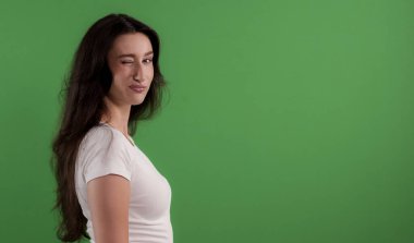 Güzel genç bir kadın yeşil ekranda göz kırpıyor ve öpücükler yolluyor