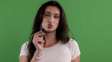 Esmer model kırmızı ruj sürüyor ve krom anahtar arka planda bir öpücük yolluyor.