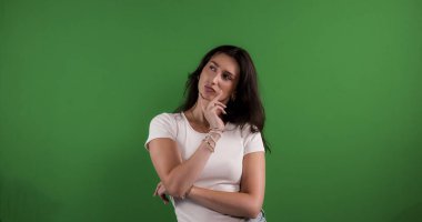 Elleri çenesinde poz veren, düşünen ve yeşil arka plana bakan manken.