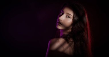 Yüzünde ve vücudunda renkli ışıklar ve gölgeler olan güzel bir mankenin stüdyo portresi.