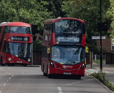 LONDON, İngiltere - 5 AĞUSTOS 2025 - İki kırmızı Arriva Londra çift katlı otobüs Sunray Avenue, Londra, İngiltere yakınlarındaki bir sokakta sürüyor