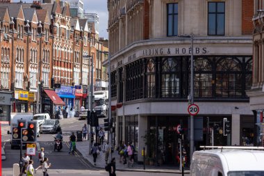 LONDON, UK - 5 AĞUSTOS 2025 - Londra, İngiltere 'deki Arding ve Hobbs Binası yakınlarındaki güneşli bir yaz gününde yayalar ve araçlar