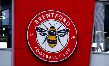LONDON, UK - 5 AĞUSTOS 2025 - Brentford FC logosuna yakın çekim, takımın Londra, İngiltere 'deki stadyumlarının kırmızı bir duvarındaki The Bees takma adını sembolize ediyor.