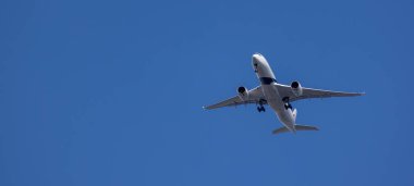 LONDON, İngiltere - 5 AĞUSTOS 2025 - Açık mavi gökyüzünde uçan modern yolcu uçağı, seyahat ve turizm konsepti