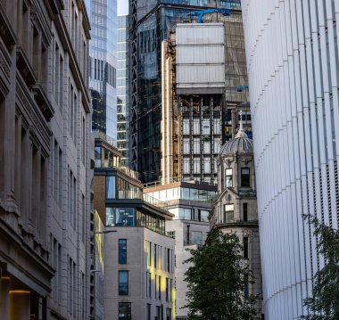 LONDON, İngiltere - 5 AĞUSTOS 2025 - Londra 'nın finans bölgesindeki modern cam gökdelenlerden yansıyan güneş ışığı, çevredeki tarihi binaları aydınlatıyor