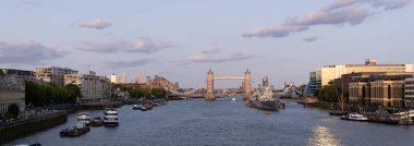 LONDON, UK - 5 AĞUSTOS 2025 - Tower Bridge 'in günbatımında HMS Belfast ve Londra' da yelken açan bazı teknelerle Thames 'e yansıyan panoramik görüntüsü